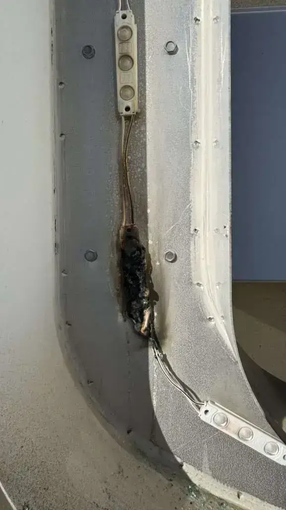 Burned and shorted LED module discovered inside a channel letter, with visible flame and heat damage to the wiring and letter casing